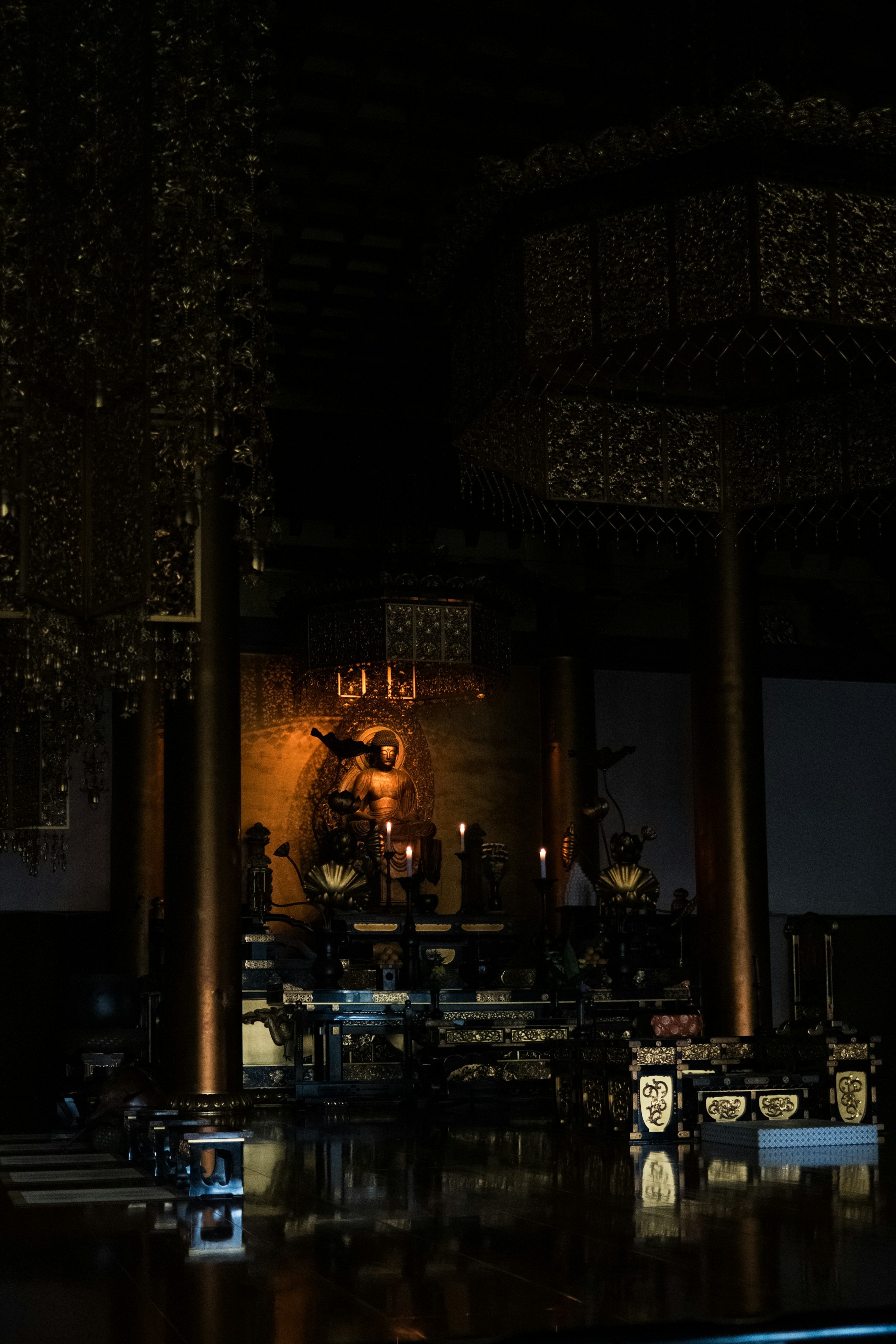 Buddha auriu pe altar într-un templu întunecat, lumină caldă de lumânări